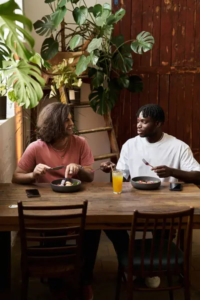 Two handsome individuals share a joyful meal, laughing and engaging in heartfelt conversation. — Stock Photo
