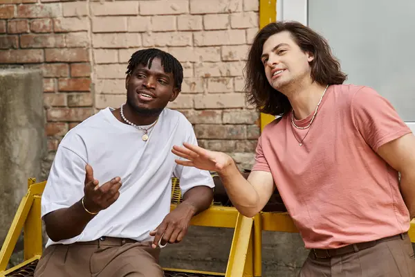 Two handsome men share joyous moments while seated outside a cafe, immersed in conversation. — Stock Photo