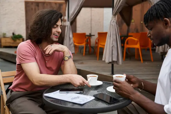 Dois homens bonitos compartilham um momento alegre sobre o café em um café encantador, imerso em conversa. — Fotografia de Stock