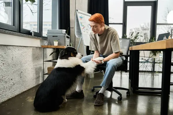 Young red haired man bonds with his dog during office hours, mixing work and companionship. — Stock Photo