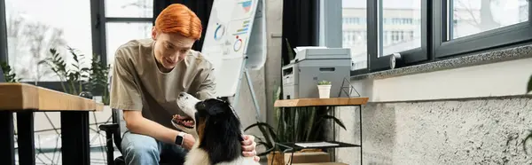 Молодой человек с рыжими волосами и дружелюбной собакой на работе среди зелени. — стоковое фото