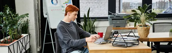 Young man with red hair works in a stylish office, surrounded by greenery. — Stock Photo