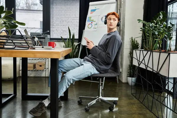 Bright office with a young red haired man focused on work and listening to music. — Stock Photo