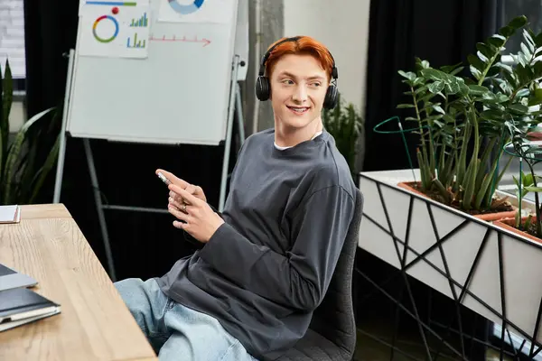 A young man with red hair diligently works in a modern office, showcasing his commitment. — Stock Photo
