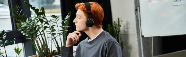 Young man with red hair listens intently in an inspiring office. — Stock Photo