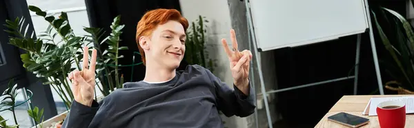 A young man with red hair engages with enthusiasm while working in a contemporary office space. — Stock Photo