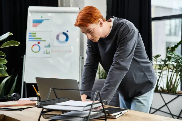 Dedicated young man with red hair engaged in work tasks at a stylish office desk — Stock Photo