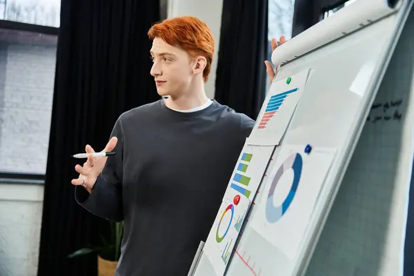 Young man with red hair engages colleagues by sharing insights and displaying charts in an office. — Stock Photo