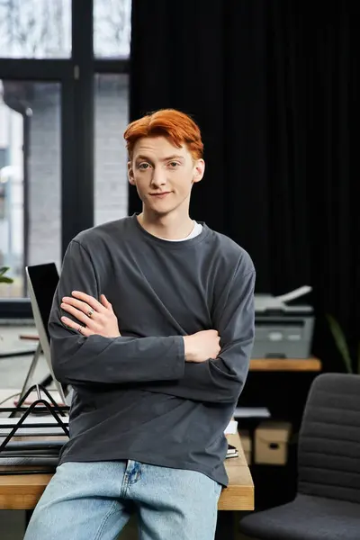 A young man with red hair stands confidently in a bright office space, exuding professionalism. — Stock Photo