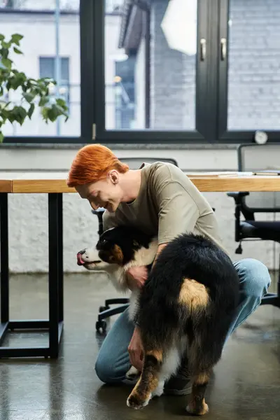 Un giovane uomo dai capelli rossi si inginocchia al lavoro per salutare con gioia il suo cane. — Foto stock