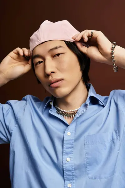 Jeune homme asiatique pose avec confiance, montrant une tenue à la mode et des accessoires dans un studio. — Photo de stock