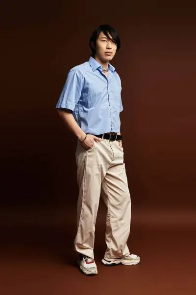 Un joven posa con confianza en un atuendo elegante sobre un rico telón de fondo, encarnando la moda. — Stock Photo