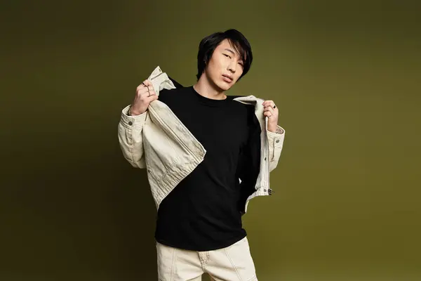 A confident young man poses in a studio, displaying his trendy outfit and unique style. — Stock Photo