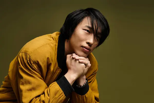A young, handsome man poses thoughtfully in a trendy outfit within a vibrant studio space. — Stock Photo