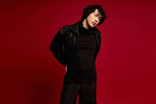 Stylish young Asian man in black poses against a red background. — Stock Photo