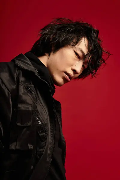 Young asian man strikes a fashion pose in a studio. He wears a stylish, dark-colored ensemble. — Stock Photo