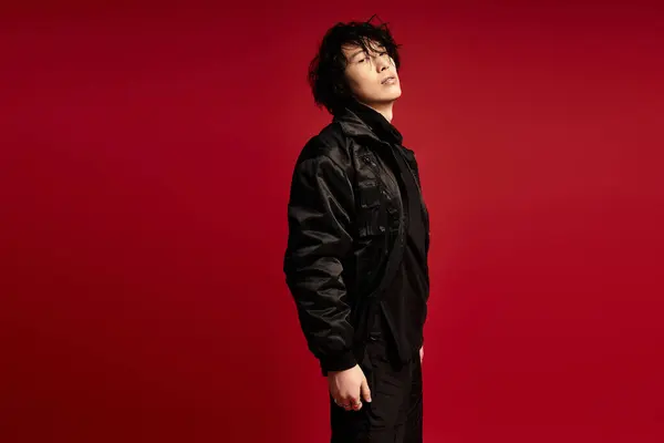 Stylish young man in black strikes a confident pose in studio. — Stock Photo