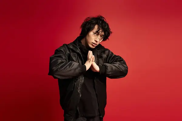 A stylish young man in black attire posing in a red studio. — Stock Photo
