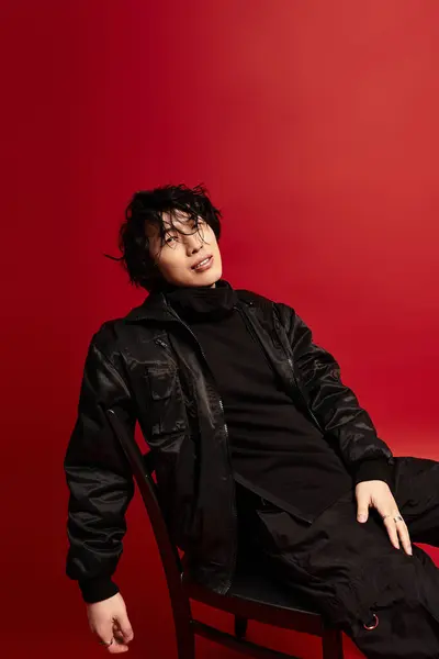 Un joven, guapo, elegante hombre asiático posa con confianza sobre un rico telón de fondo rojo en un estudio. — Stock Photo