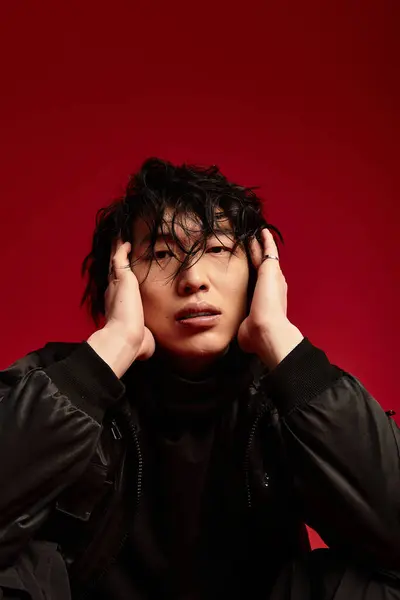 Asian man with stylish hair, wearing a fashionable outfit, posing dramatically in a studio setting. — Stock Photo