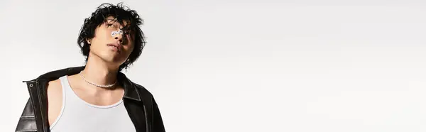 Young asian man with leather jacket and pearl necklace looks up with a confident pose in a studio, banner — Stock Photo