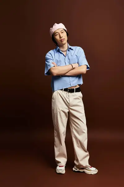 In a trendy studio, a young Asian man showcases his fashionable outfit with charm and poise. — Stock Photo