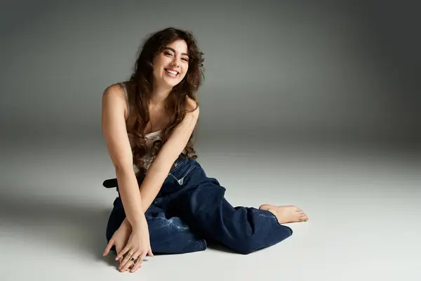 A young woman with flowing hair exudes confidence in trendy attire on a studio floor. — Stock Photo