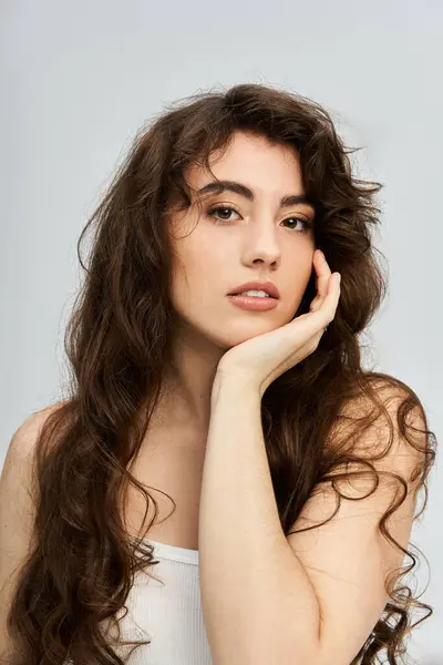 Charming young woman with long curly hair poses gracefully, radiating confidence and style. — Stock Photo