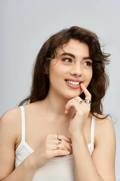 Élégante jeune femme aux cheveux fluides pose avec un sourire charmant, mettant en valeur ses anneaux. — Photo de stock