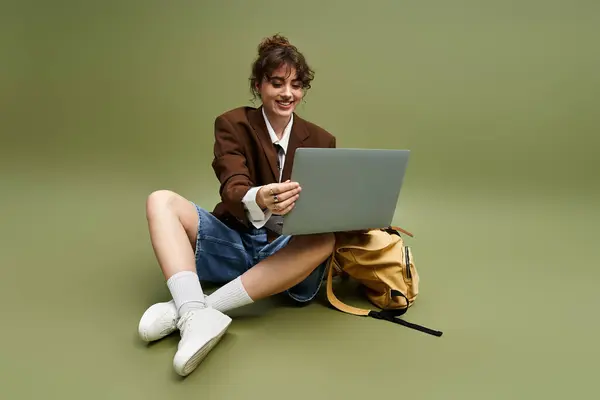 A young pretty woman in fashionable attire enjoys her time with a laptop while sitting casually. — Stock Photo