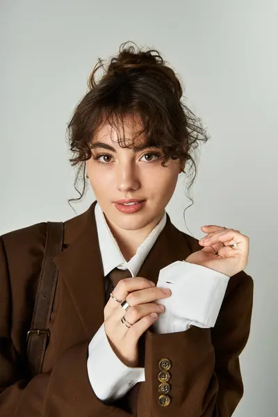Charmante junge Frau spielt mit ihrem stylischen Outfit, während sie in einem sauberen, modernen Studioraum posiert. — Stockfoto