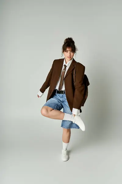 In a minimalist studio, a stylish woman shows off her chic outfit with shorts and a blazer. — Stock Photo