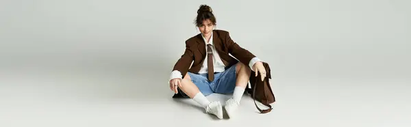 A young woman smiles playfully while showcasing her trendy outfit as she sits on the floor. — Stock Photo