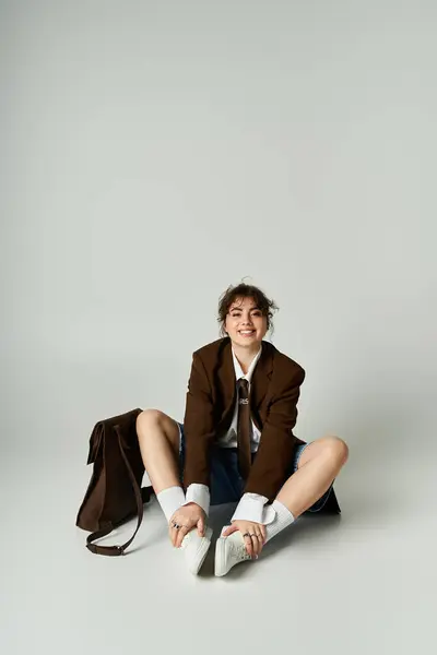 Joyeuse jeune femme s'assoit confortablement dans une tenue élégante, respirant confiance et charisme à l'intérieur. — Photo de stock