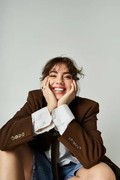 A young woman with a playful smile showcases her fashion sense while seated comfortably. — Stock Photo