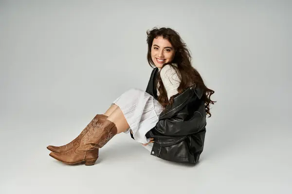 A confident young woman showcases her trendy outfit and stylish accessories in a studio. — Stock Photo