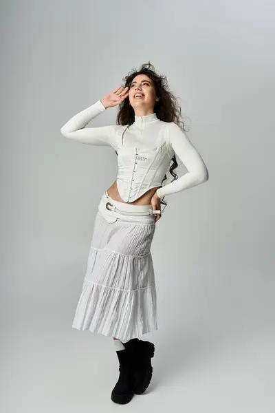 A young woman displays her fashionable attire while posing playfully in a bright studio space. — Stock Photo