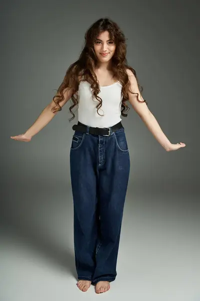 Confident young woman poses in stylish attire against a studio backdrop, exuding grace. — Stock Photo