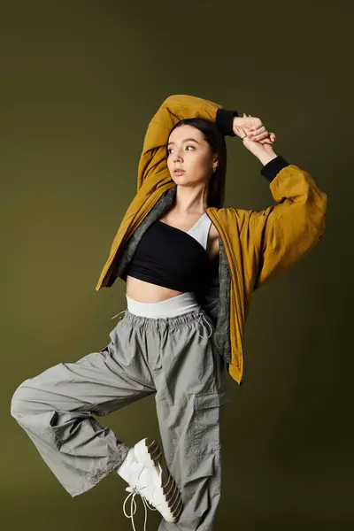 Young woman in stylish outfit strikes a dynamic pose against a bold backdrop, exuding confidence. — Stock Photo