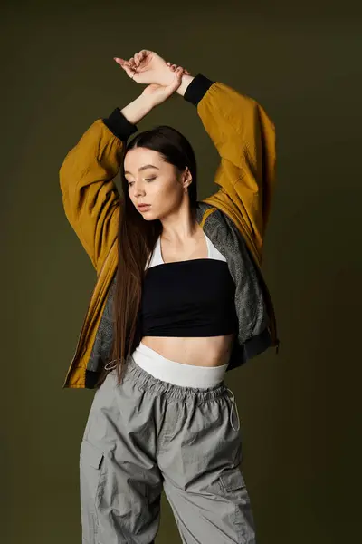 Mujer joven confiada golpea una pose dinámica en un atuendo urbano elegante contra un fondo rico — Stock Photo