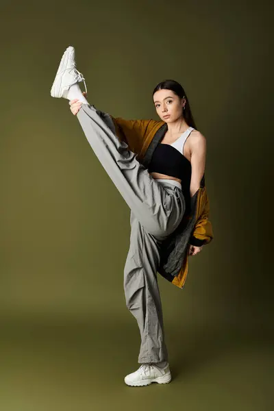 A young woman in trendy attire poses confidently in a studio, showcasing her fashion sense. — Stock Photo