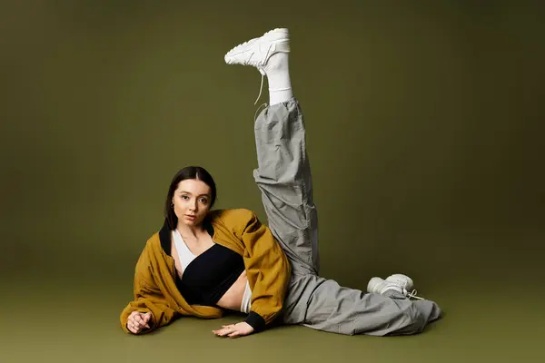 A young woman in stylish attire poses gracefully with one leg raised, radiating confidence. — Stock Photo