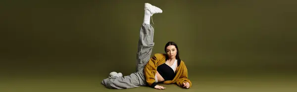 Young pretty woman lounges stylishly against a pale green backdrop, showcasing chic fashion — Stock Photo