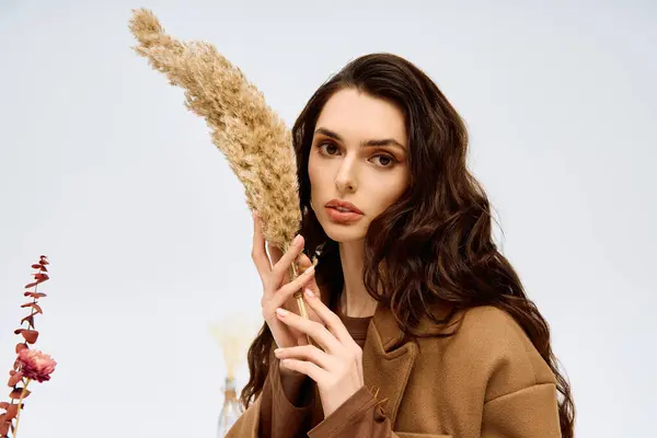 A young woman with long brown hair holds a delicate plant. — Stock Photo