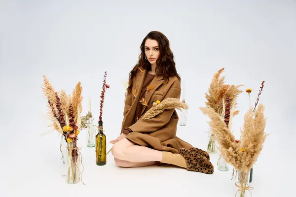 A young woman with long brown hair poses elegantly in a coat among spring flowers. — Stock Photo