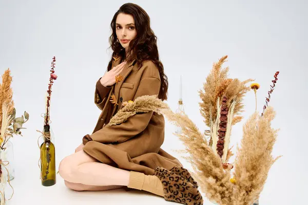 Une jeune femme aux longs cheveux bruns jouit de la beauté du printemps tout en étant assise parmi les fleurs. — Photo de stock