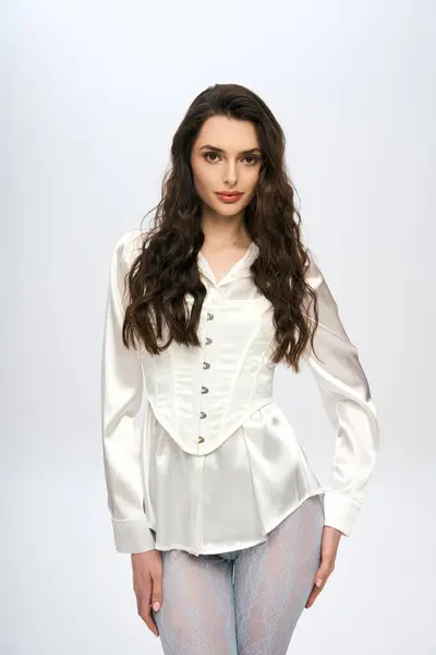 A beautiful young woman with brown hair poses gracefully in a studio. — Stock Photo