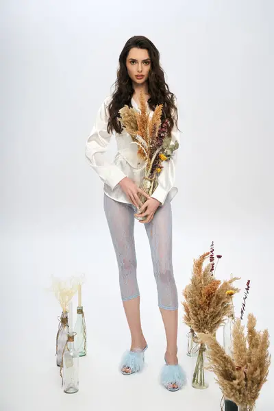 Eine schöne junge Frau mit braunen Haaren hält im Frühling Blumen in einem hellen Atelier. — Stockfoto