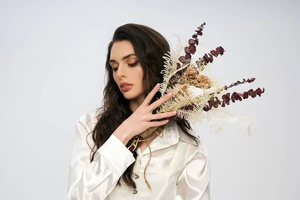 Una giovane donna dai capelli castani regge con grazia i fiori in una tranquilla atmosfera primaverile. — Foto stock