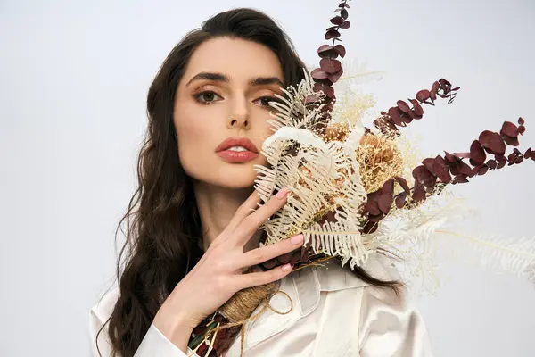 An elegant young woman with brown hair poses gracefully among a stunning array of spring flowers. — Stock Photo